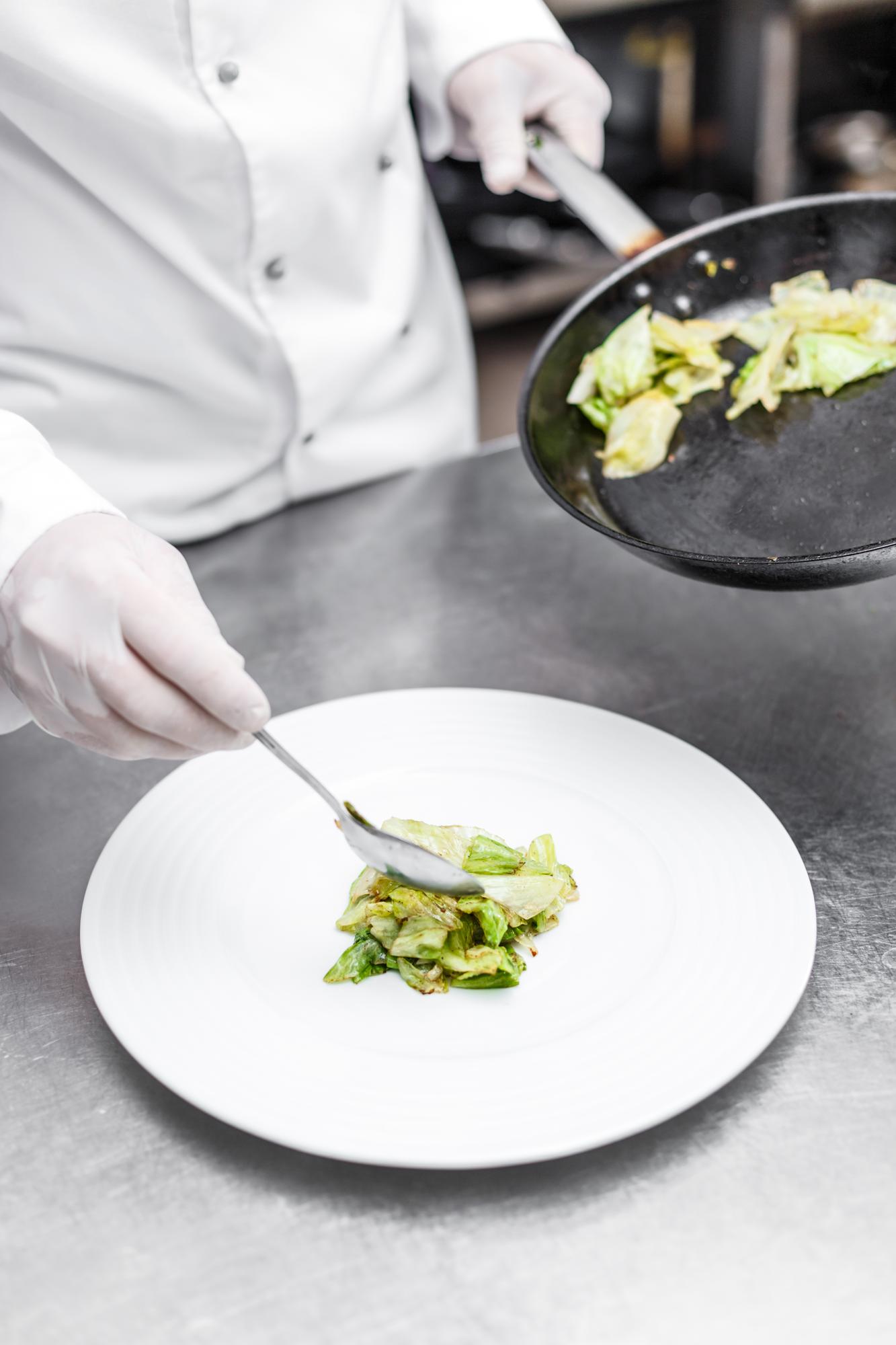 Chef preparing modern plated dish on a white counter